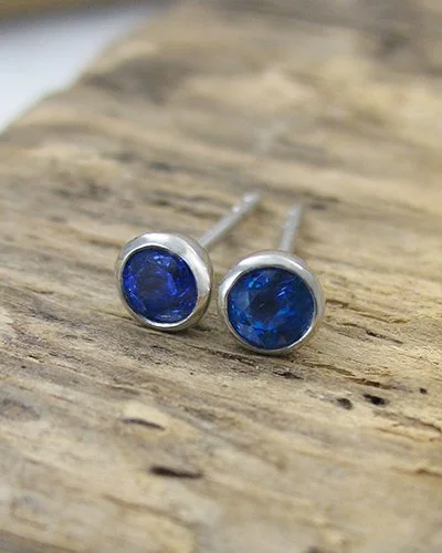 A pair of platinum rubover round blue sapphire stud earrings.jpg