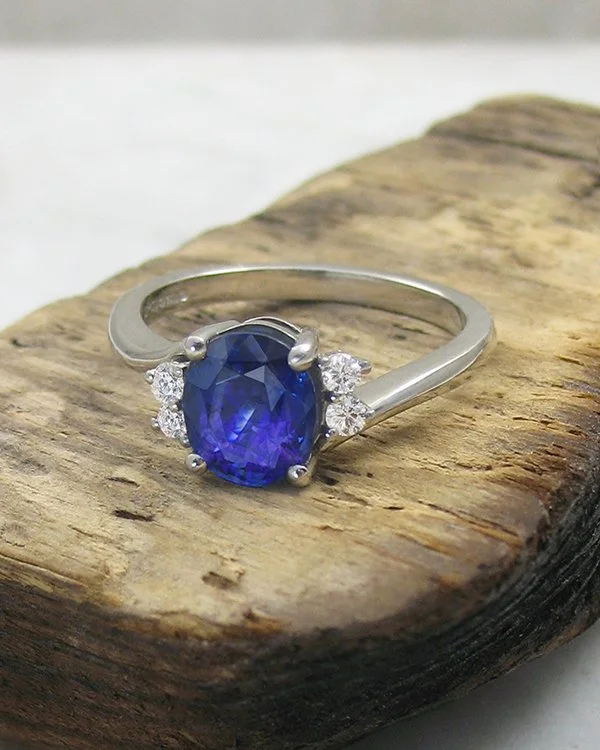 Blue sapphire engagement twist ring with offset small round diamonds on either shoulder.jpg