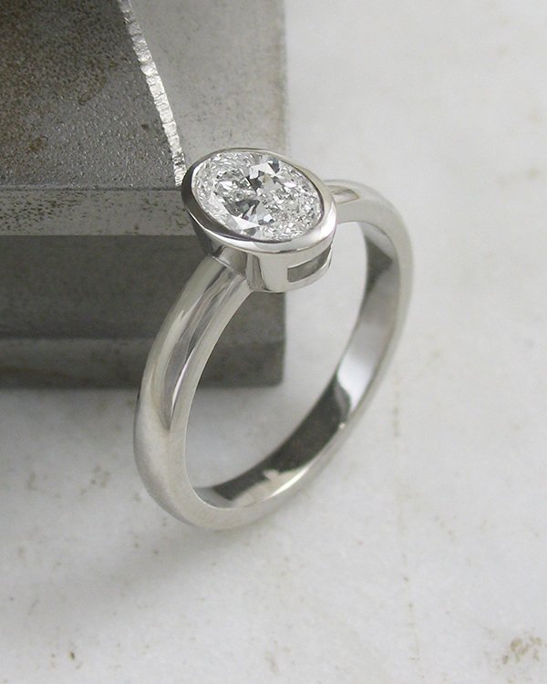 Oval shaped diamond solitaire ring in bezel setting platinum.jpg