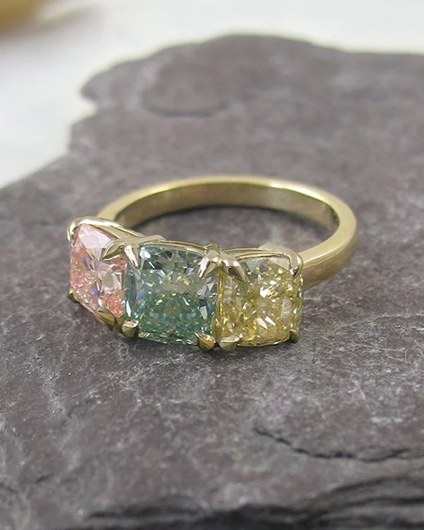 A cushion-cut fancy pink green and yellow diamond trilogy ring in 18ct yellow gold.jpg