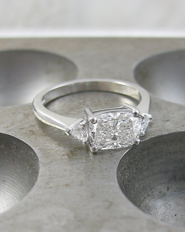 An elongated cushion diamond and trillion side stone trilogy three stone ring set in platinum 600.jpg