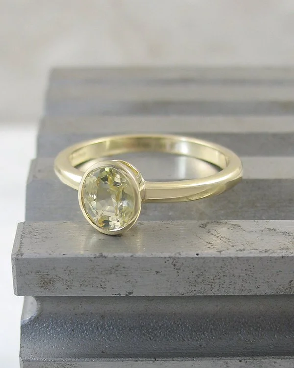 Oval yellow sapphire solitaire ring in rubover setting.jpg