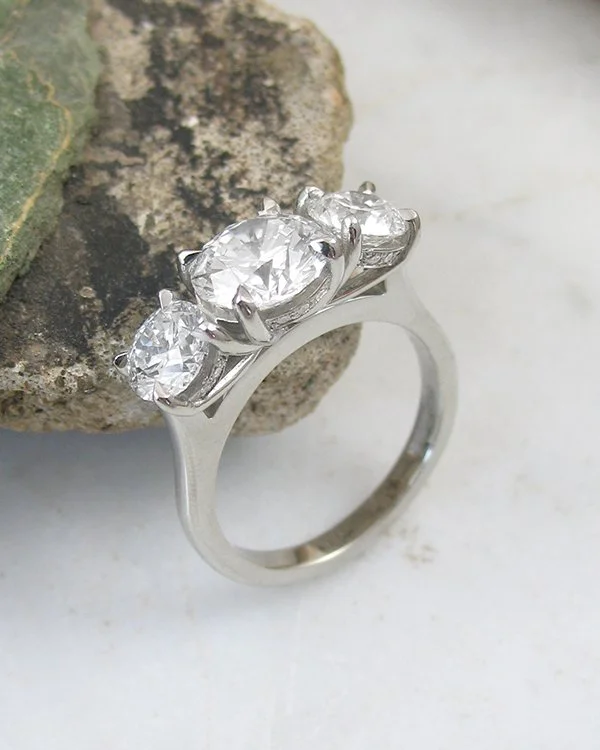 A three stone trilogy round diamond engagement ring with diamonds set into the bezels four claw platinum setting.jpg