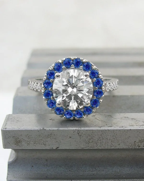 Round diamond and blue sapphire platinum halo ring with diamond set shoulders .jpg