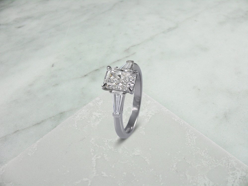 Radiant cut diamond ring with baguette diamond set shoulders