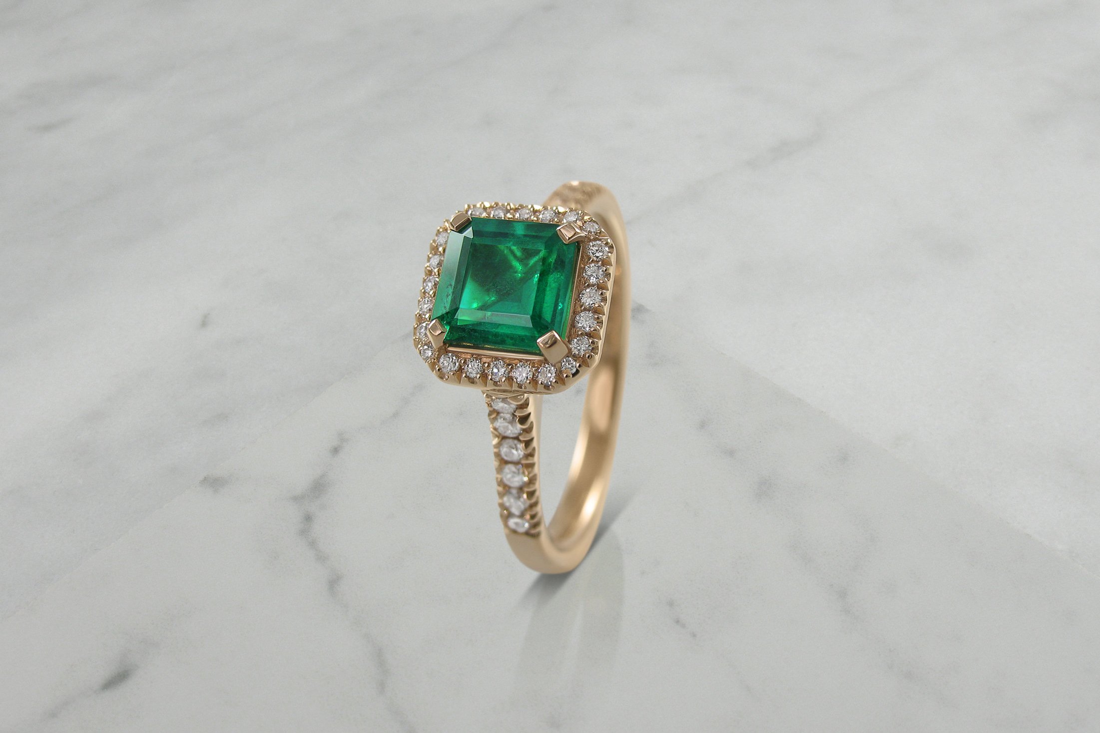 Emerald and diamond rose gold halo engagement ring