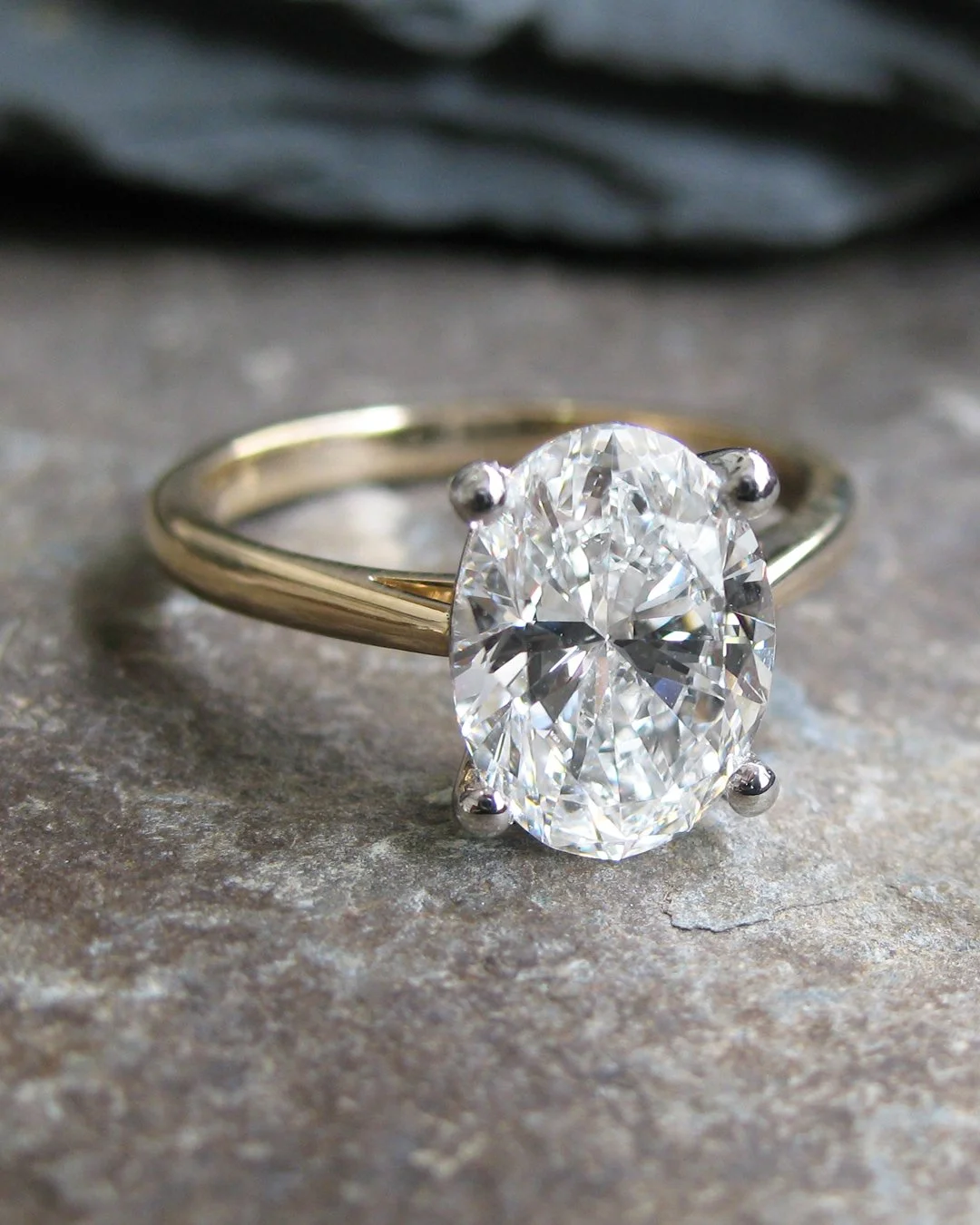 Oval diamond solitaire engagement ring with platinum claws on a yellow gold band