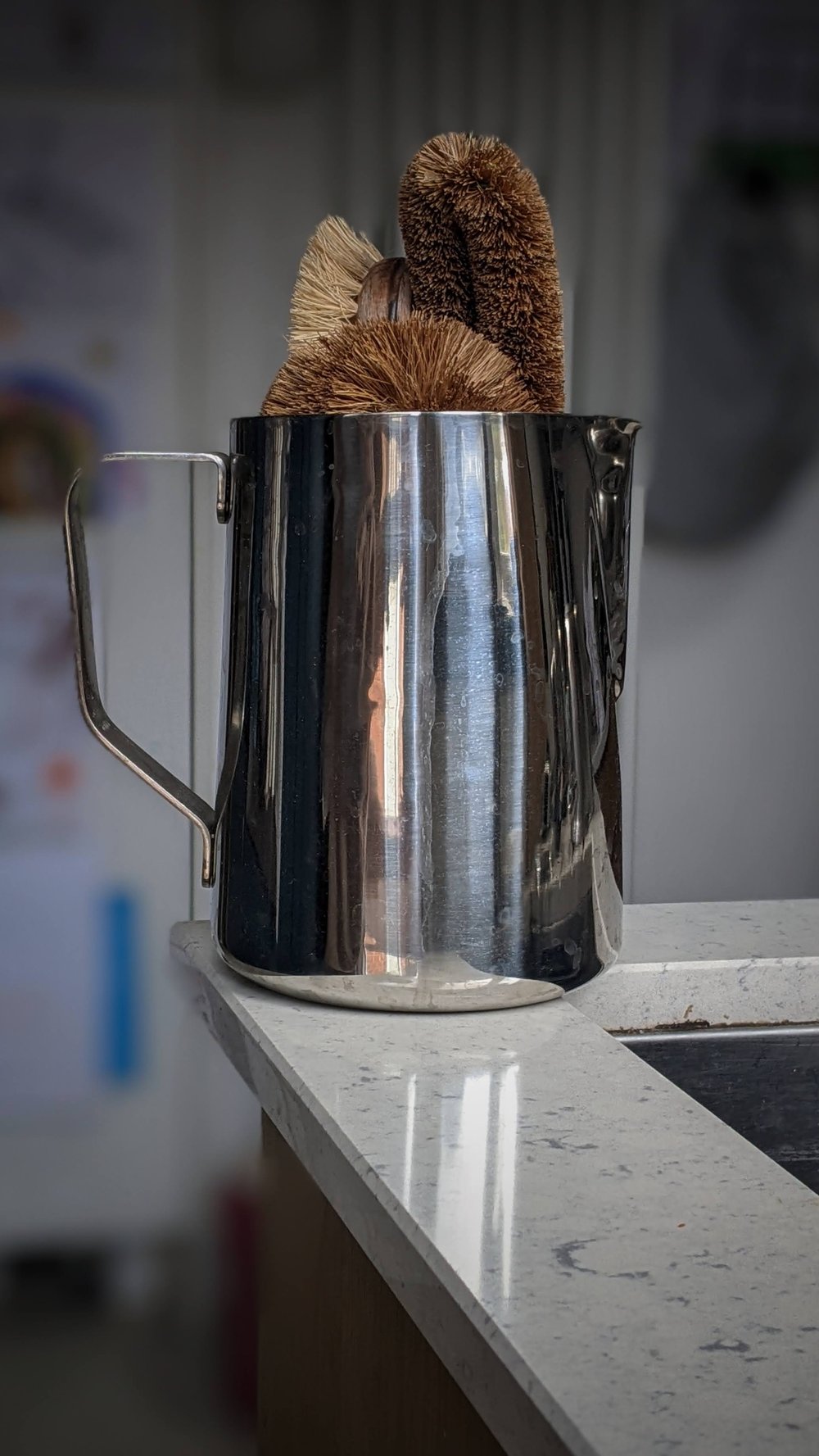 A metal barista jug found in a charity shop now used as a sink caddy