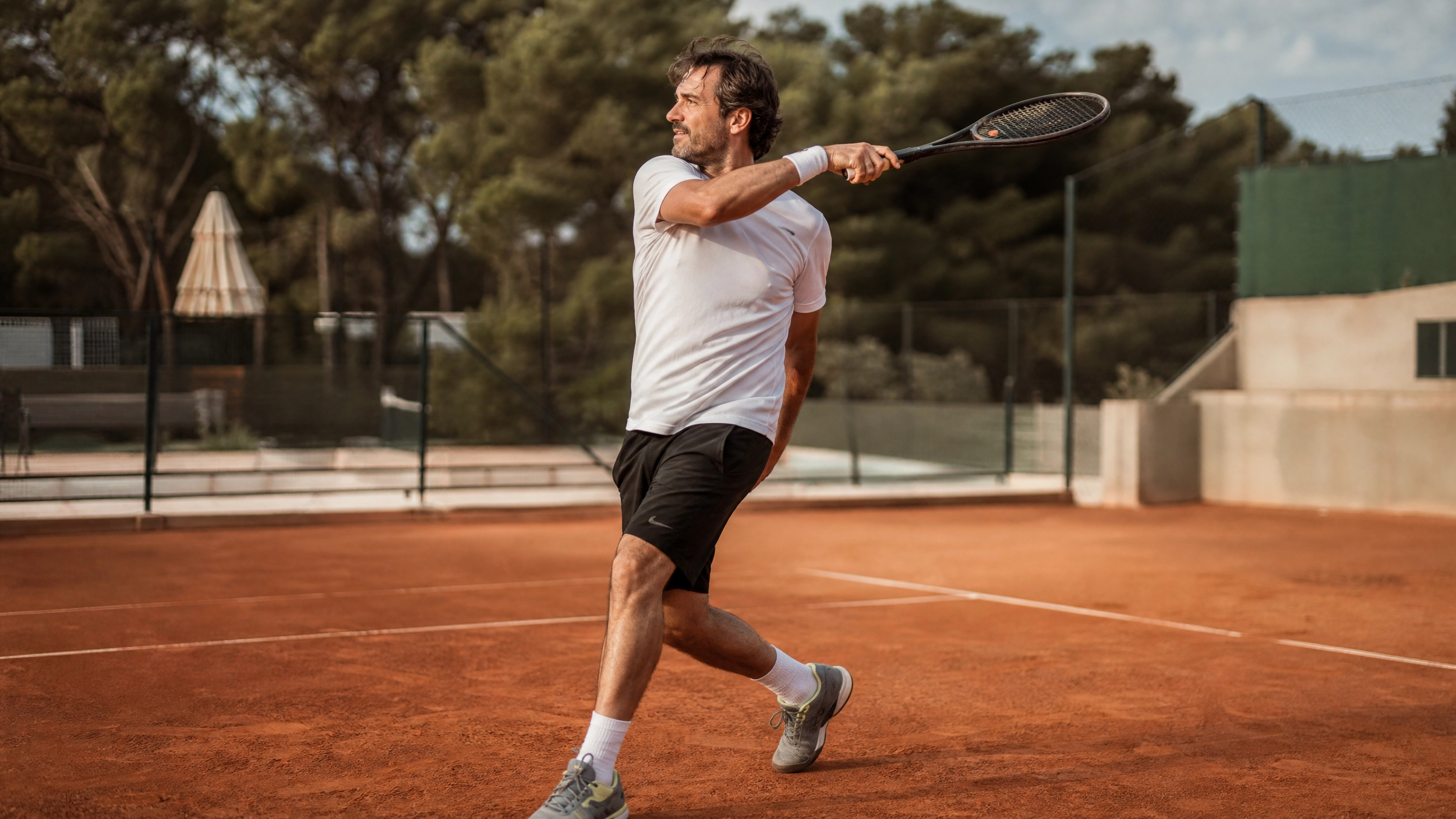 Adult tennis player on clay court mid-rally showing balanced follow-through position
