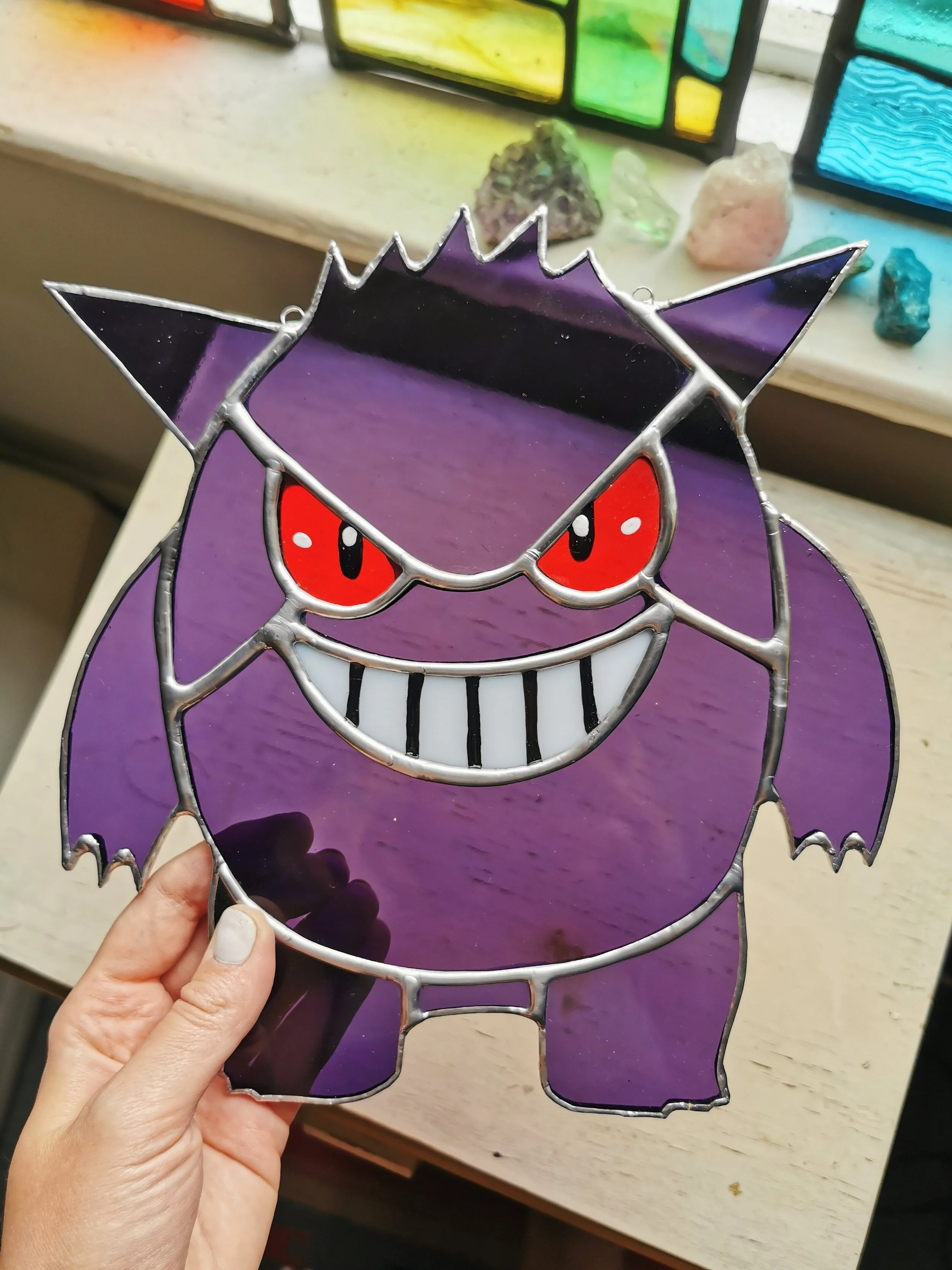 Handmade stained glass suncatcher featuring Gengar Pokémon design, perfect for hanging in a window.
