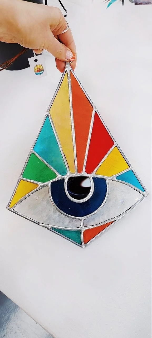 Handmade stained glass suncatcher featuring a vibrant rainbow eye design.