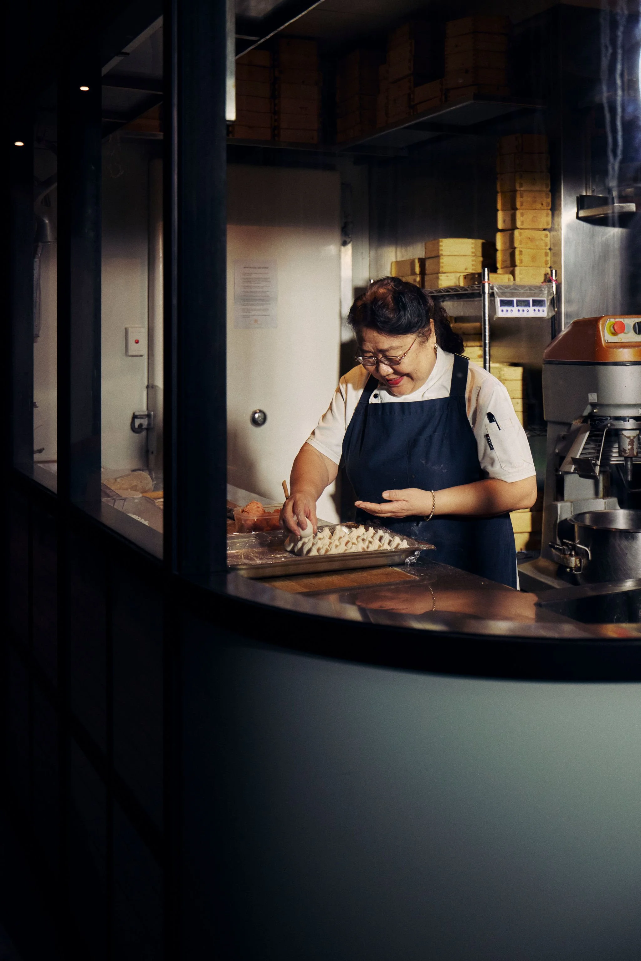 An elderly Chinese female chef is preparing dumplings