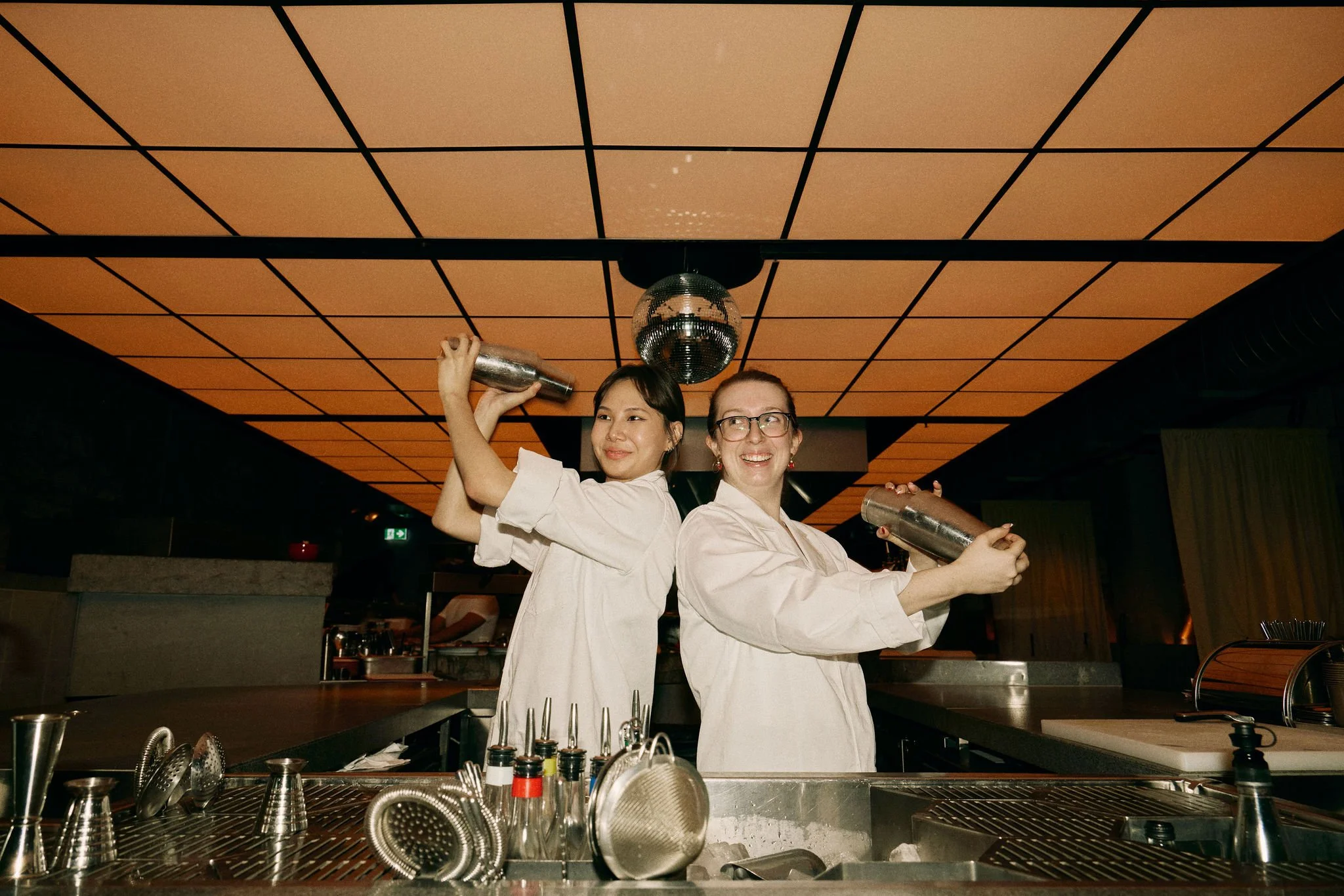 Bartenders shaking cocktails behind the bar at a Brisbane venue