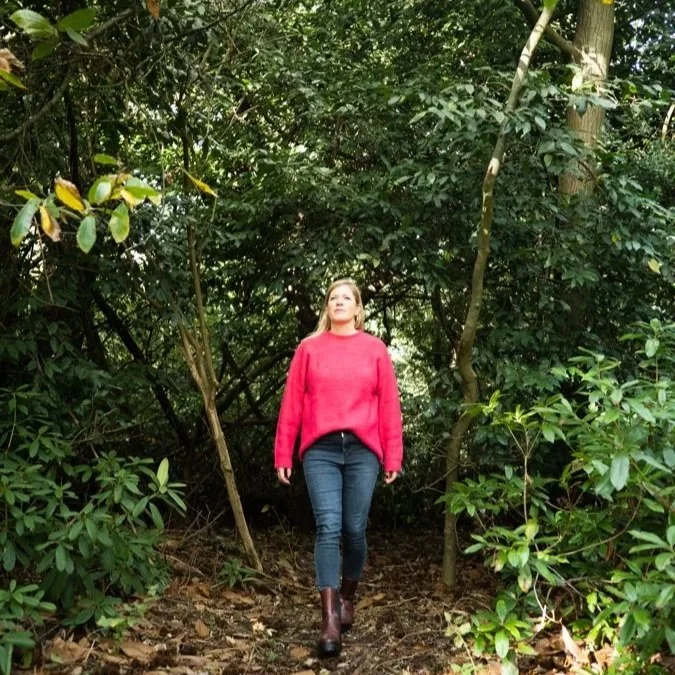women walks along forest path looking slightly skyward