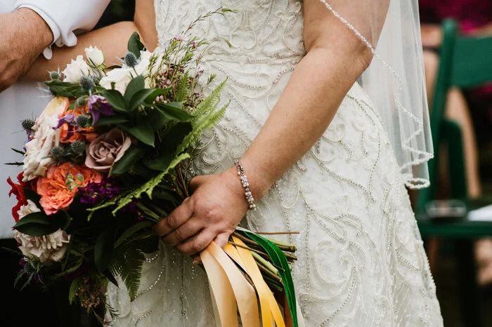 Satin and velvet ribbons in varying shades adorn the bride’s autumnal bouquet.