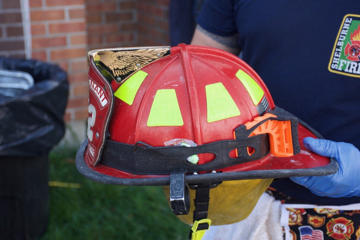  First Lieutenant Dwight Mazur holds a fire helmet with door chock. 