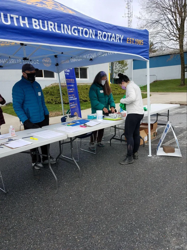 Members of the South Burlington Rotary Club give bags to a volunteer. Though the day began grey and overcast, the sky cleared and the sun began to shine as the day went on.  (Claire MacQueen/ Community News Service)