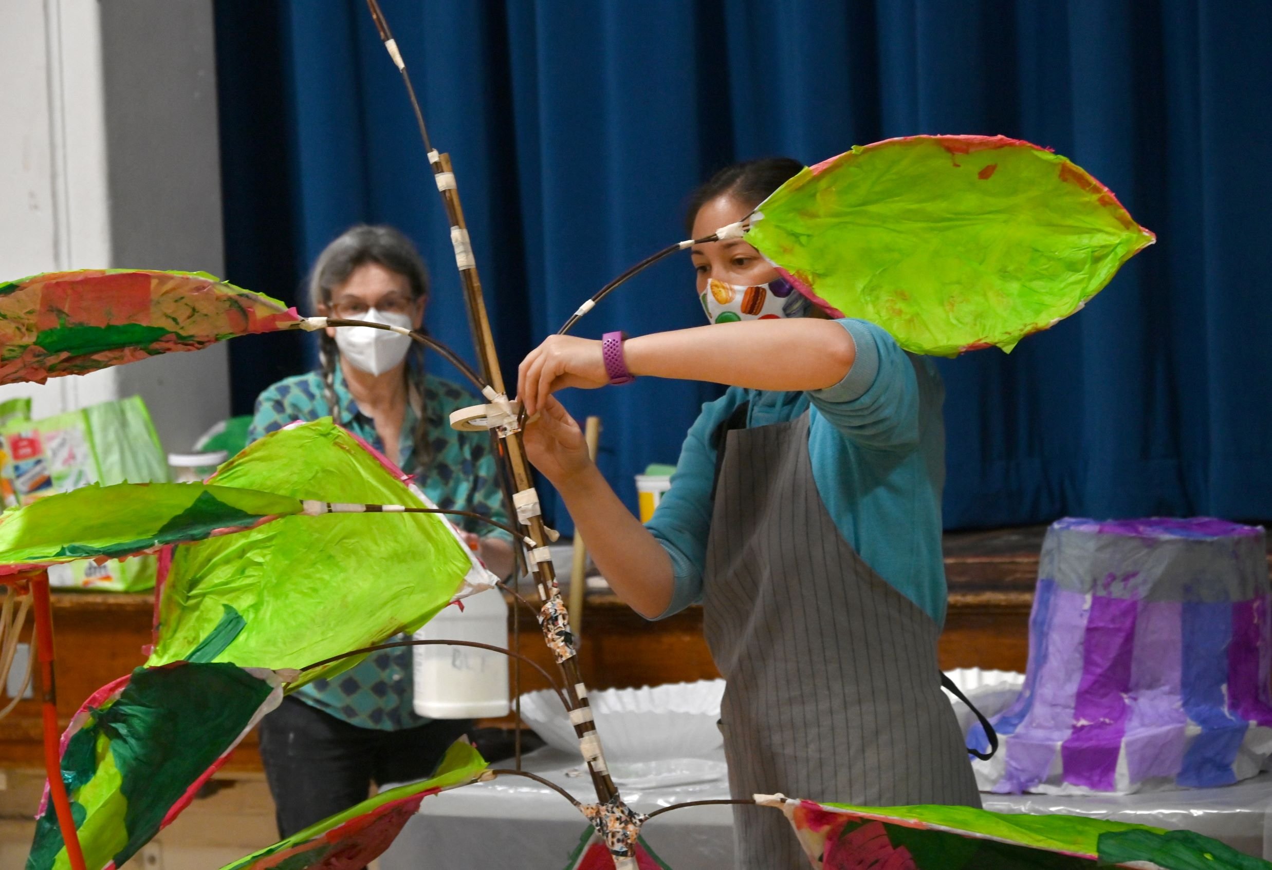  Mame McKee (left) looks on as Chiyomi McKibbin attaches leaves to her large plant lantern. Photo by Gordon Miller 