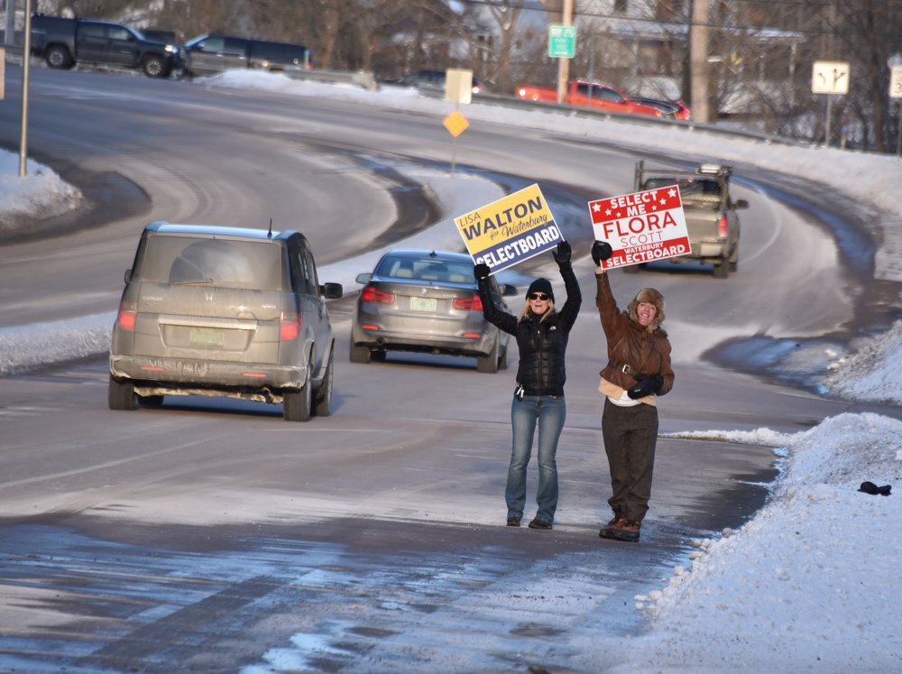   Candidates for select board Lisa Walton and Flora Scott wave to passing motorists near the I-89 northbound offramp on Monday. Photo by Gordon Miller  