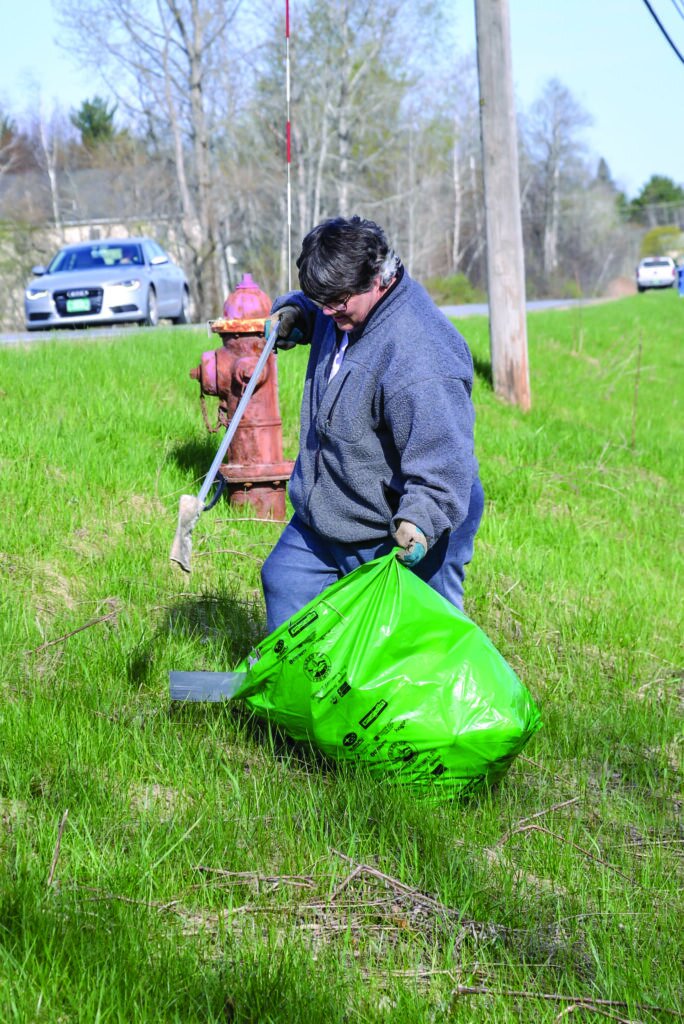  Blythe Leonard braves the steep bank along Mountain View Road to pick up trash on Green Up Day in Williston. 