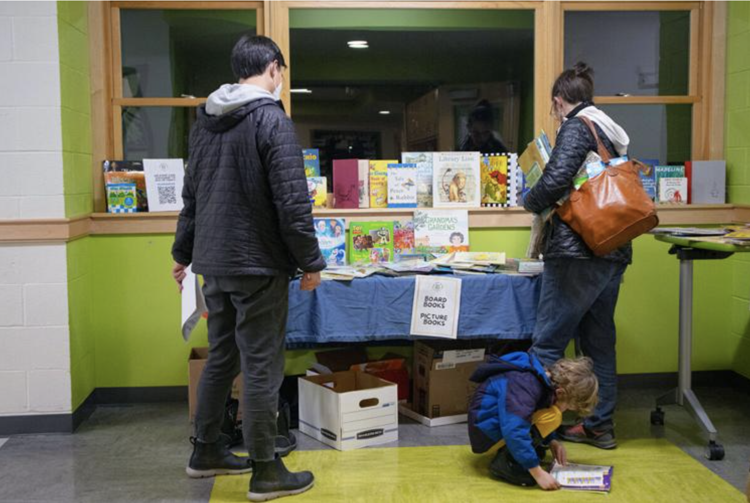  Three visitors at the Read-a-thon look at books at the Shelburne Community School on Feb.9.&nbsp;  Photo by Aylin Kursat. 