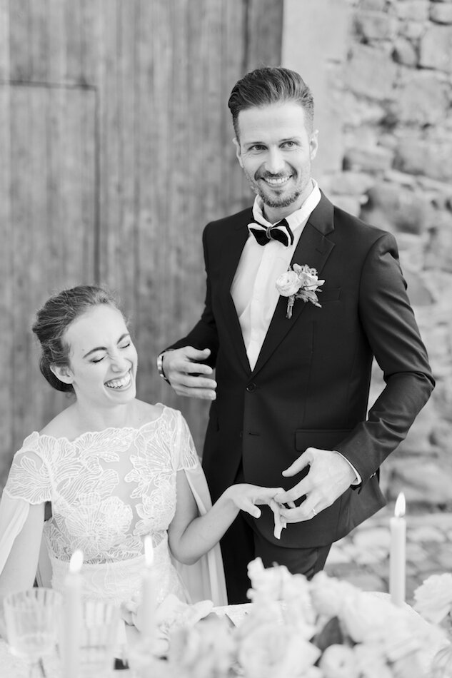 Couple de mariés en noir et blanc, riant aux éclats. 