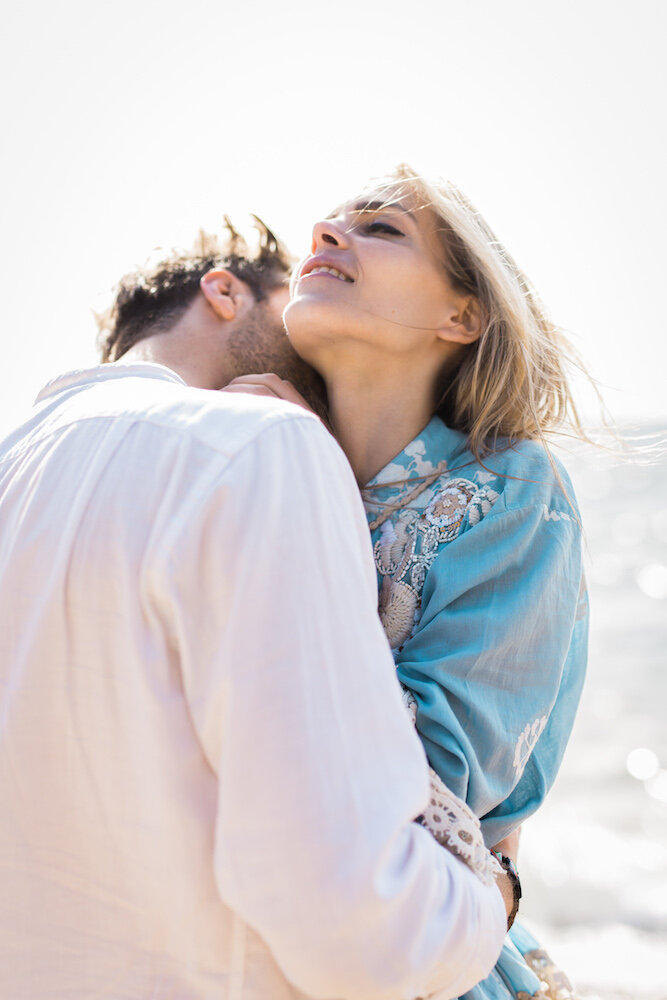 Garçon embrassant le cou de sa petite amie en bord de mer.