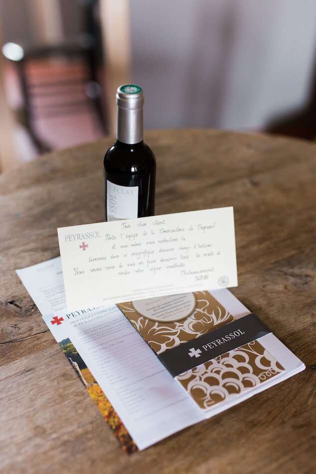 Bouteille de vin et lettre sur une table en bois à la commanderie de peyrassol.