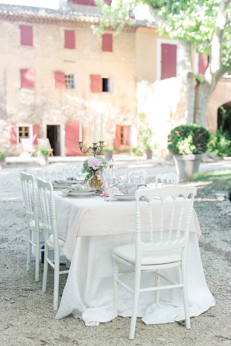 The decoration of the table with the domaine on the foreground. White chairs and white tablecloth.