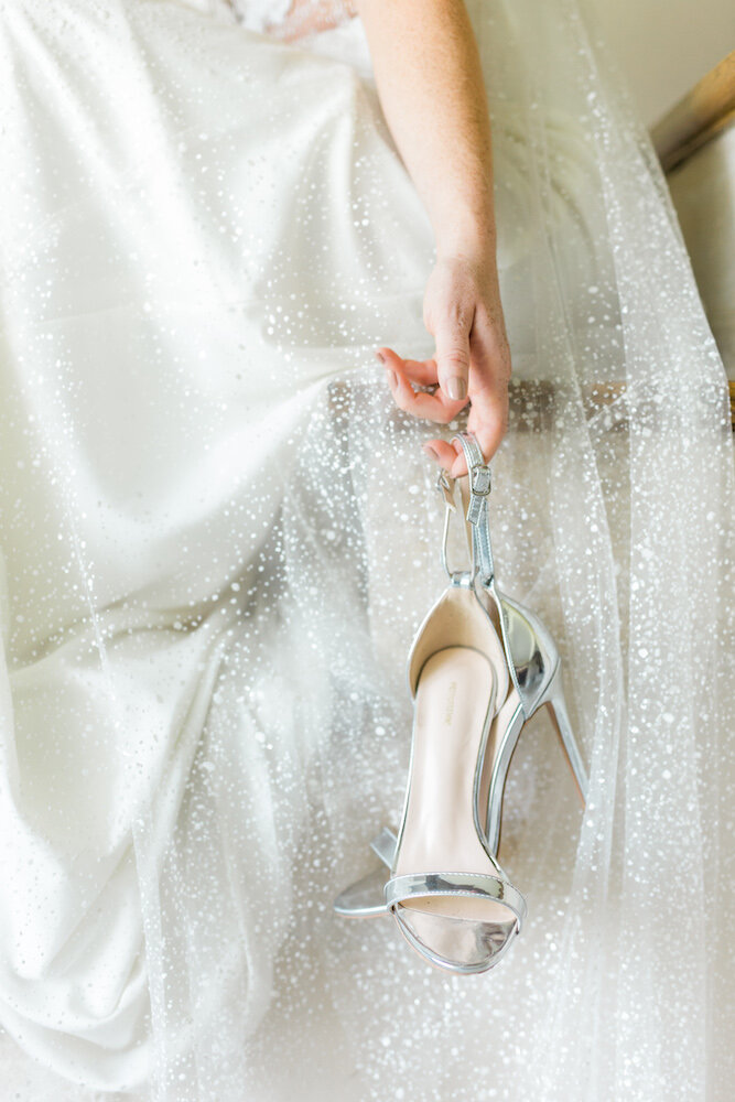 zoom sur les chaussures de la mariée qu'elle tient dans sa main pendant un shooting