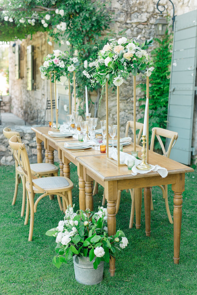 Plan sur la table et sa décoration florale verte beige et blanche, des chaises brasserie ainsi qu'une vaisselle blanche et dorée de chez maison options. 