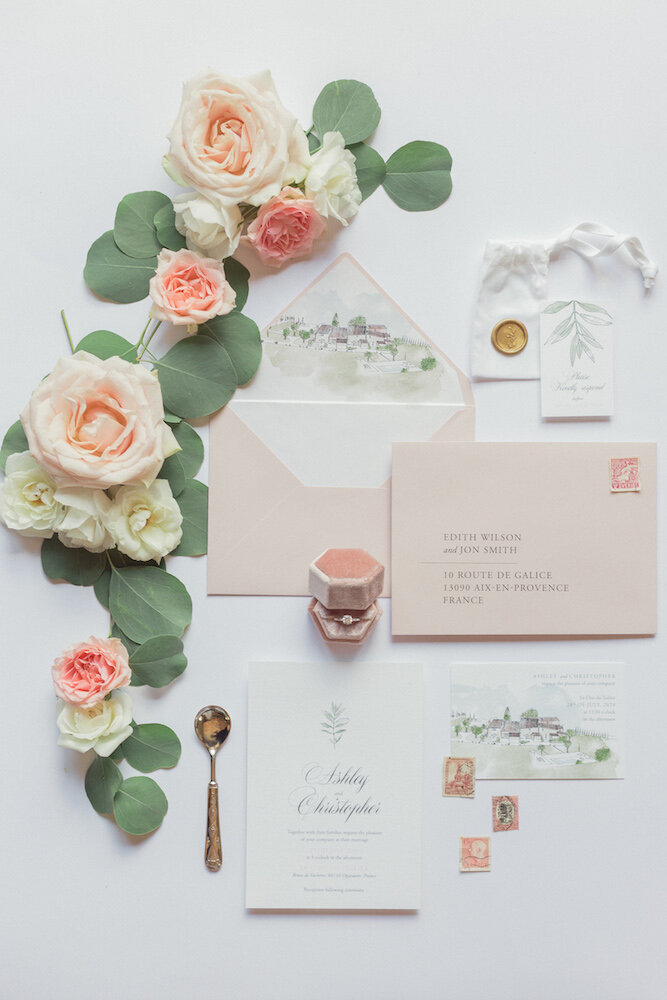 Wedding stationery and ring details on a flat lay.