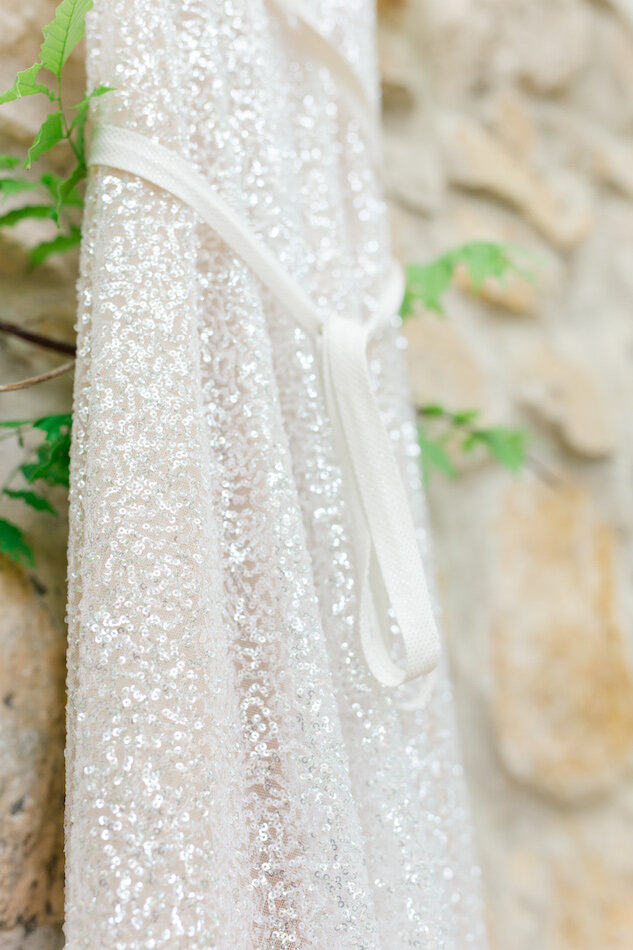 Gros plan sur la robe scintillante de la mariée.
