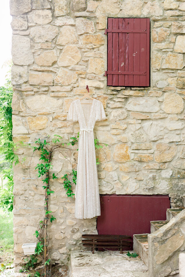 La robe de la mariée pendu contre le mur en pierre de la bâtisse.