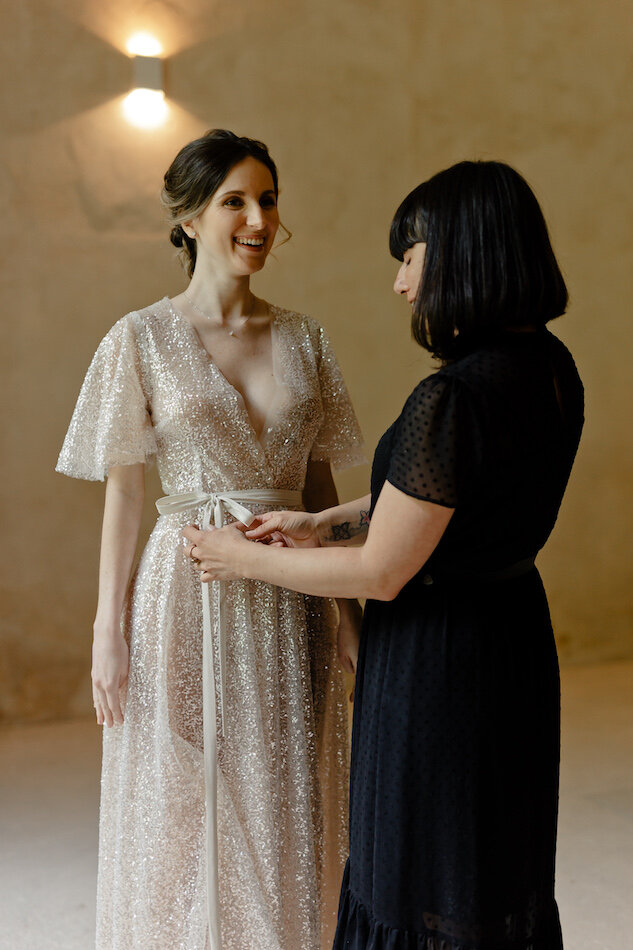 La créatrice de robe arrange la robe sur la mariée.