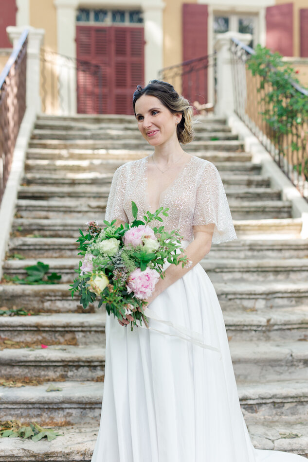 La mariée descendant les marches, bouquet à la main et allant vers son époux.