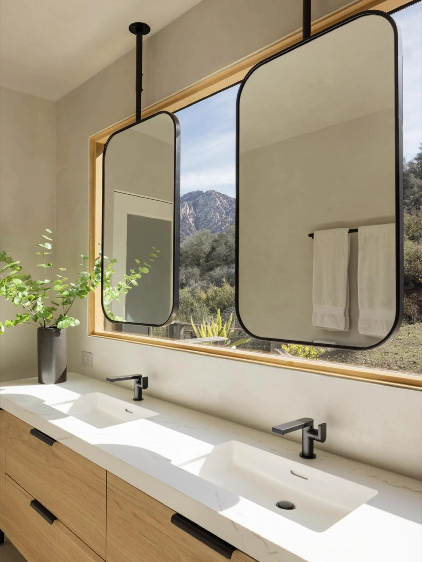 This serene master bath is a design lover's dream, featuring expansive windows that capture the majestic vistas of the Santa Monica mountains, illuminating the space with abundant natural light. A beautiful blend of style and functionality that showc