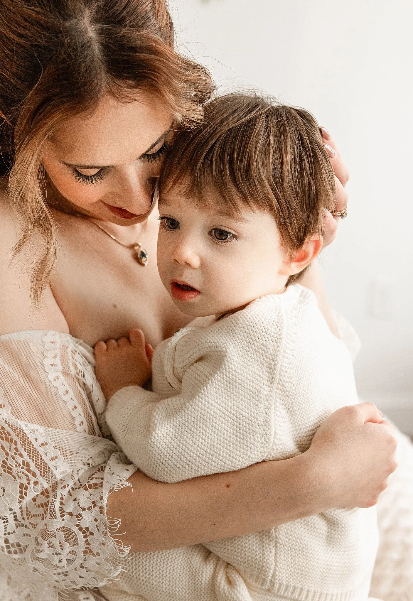 family lifestyle photo of a mom holding her toddler on her lap while giving him cuddles with their faces close for a sweet moment