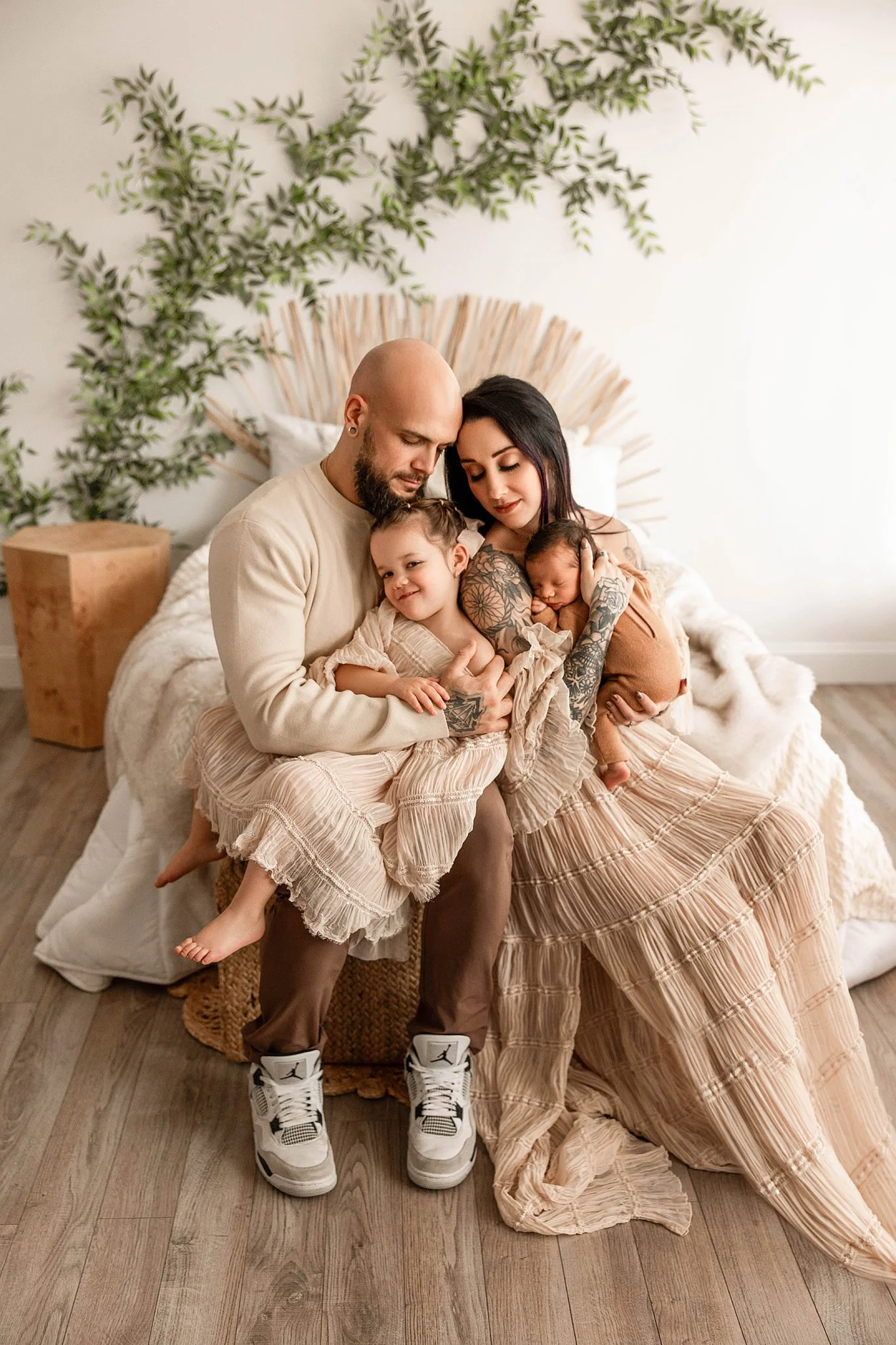 in-studio family photo with newborn baby and big sister on mom and dad's lap, with everyone cuddling in a first family photo