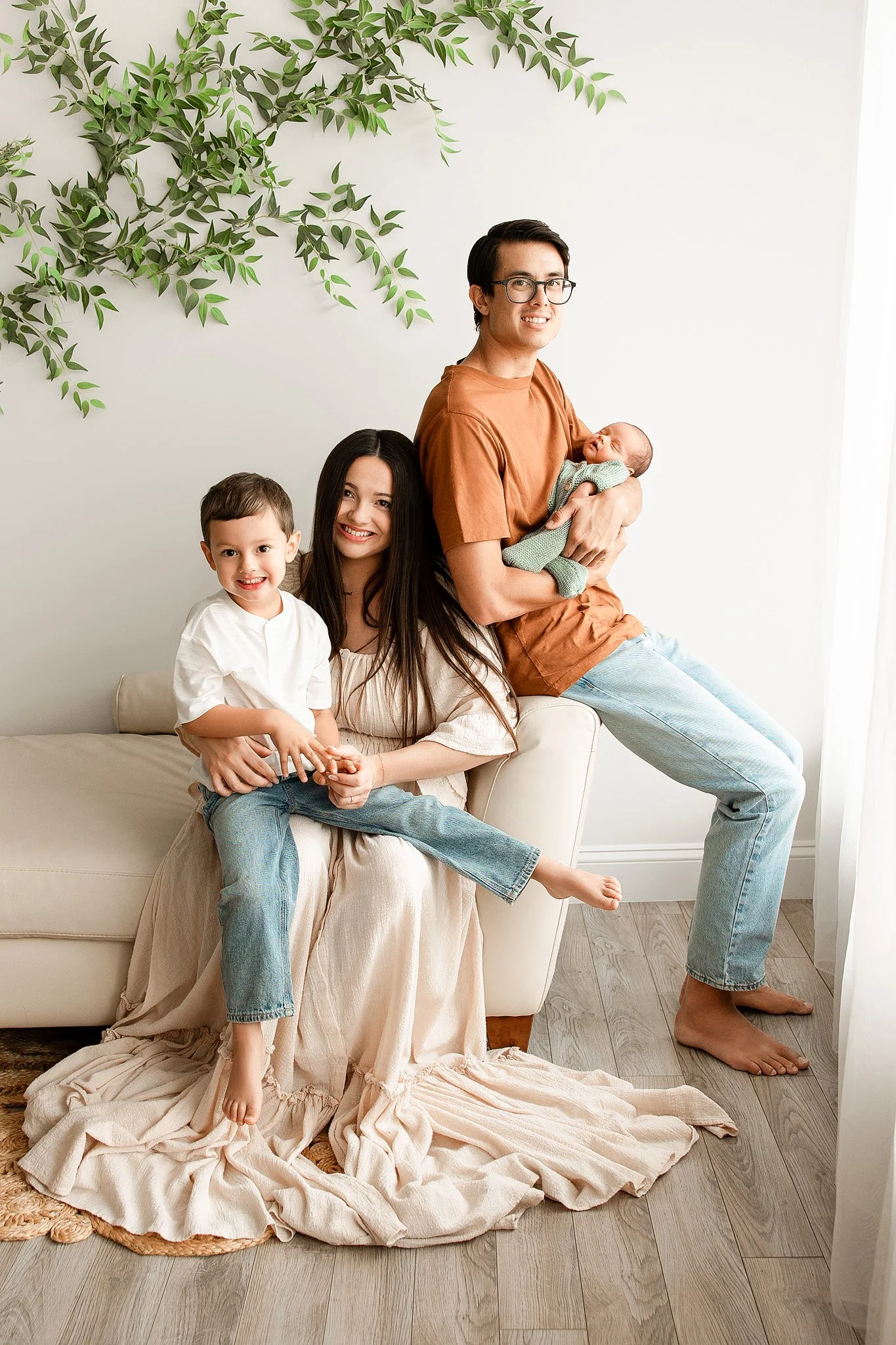 bright and airy newborn photography studio with family of four posing and cozy