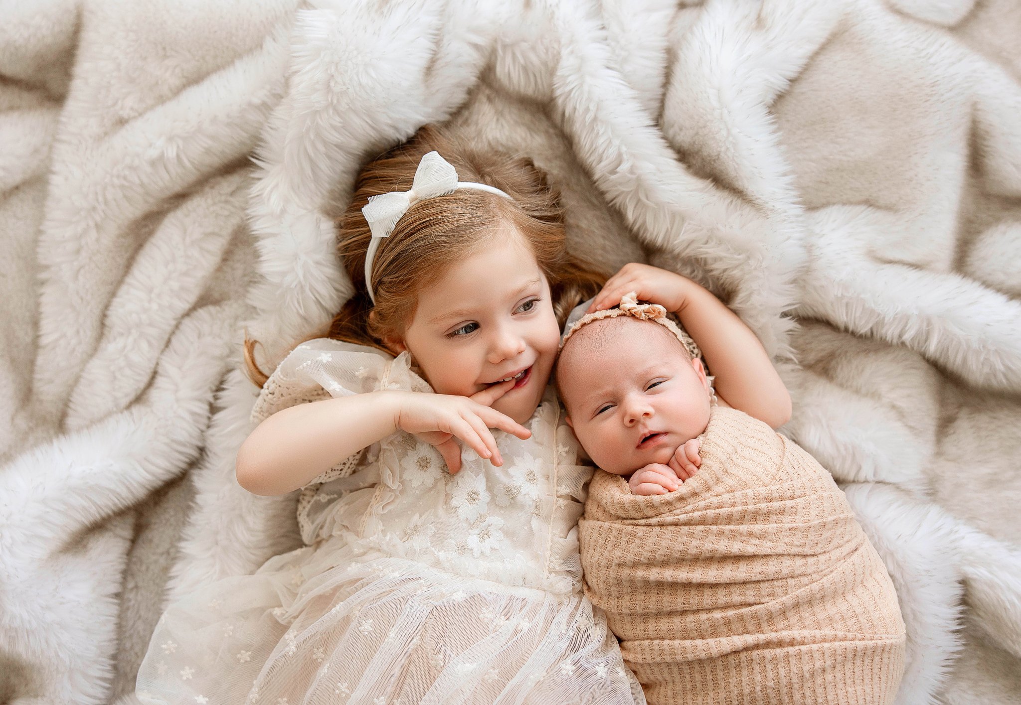 big sister holding his newborn baby during a relaxed studio photography session