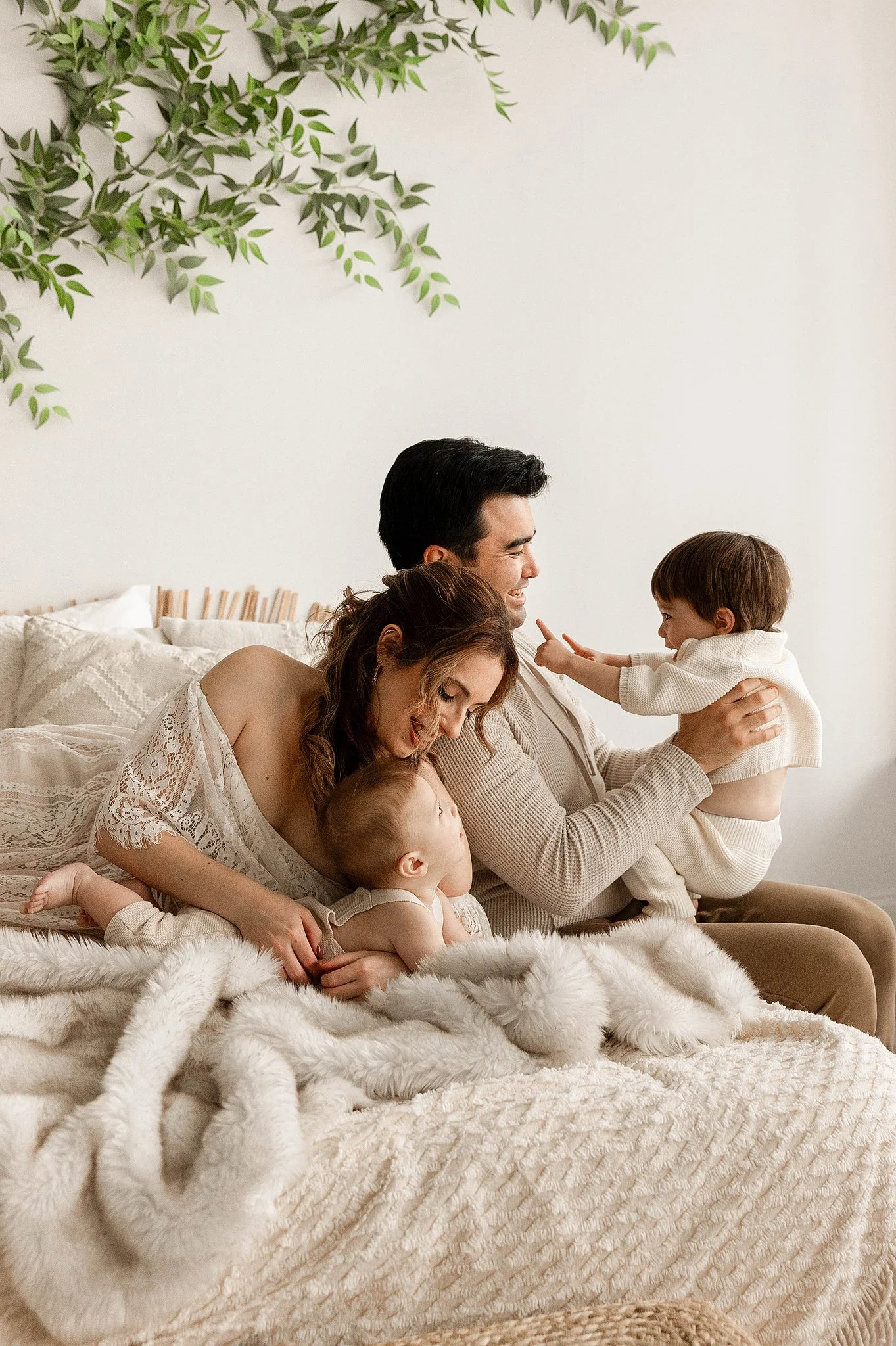family of four cozy on a ivory blanket in a natural light studio being cozy and cuddly with laughter for their lifestyle pictures
