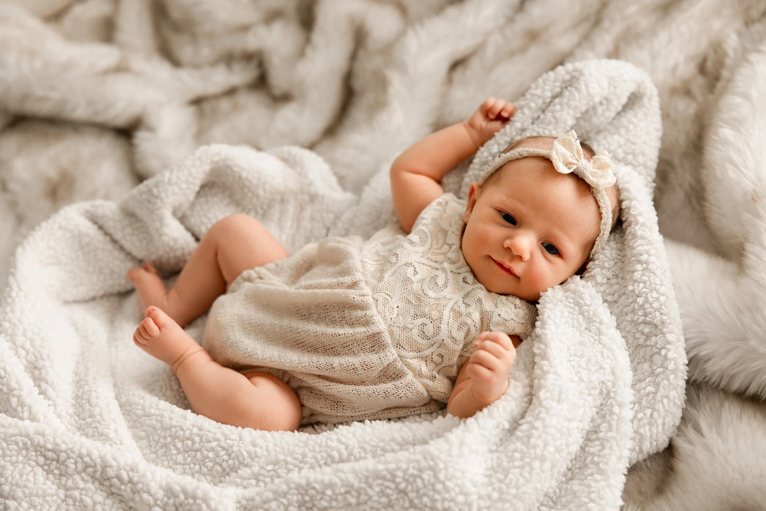 newborn baby girl in ivory outfit and soft blankets for newborn pictures