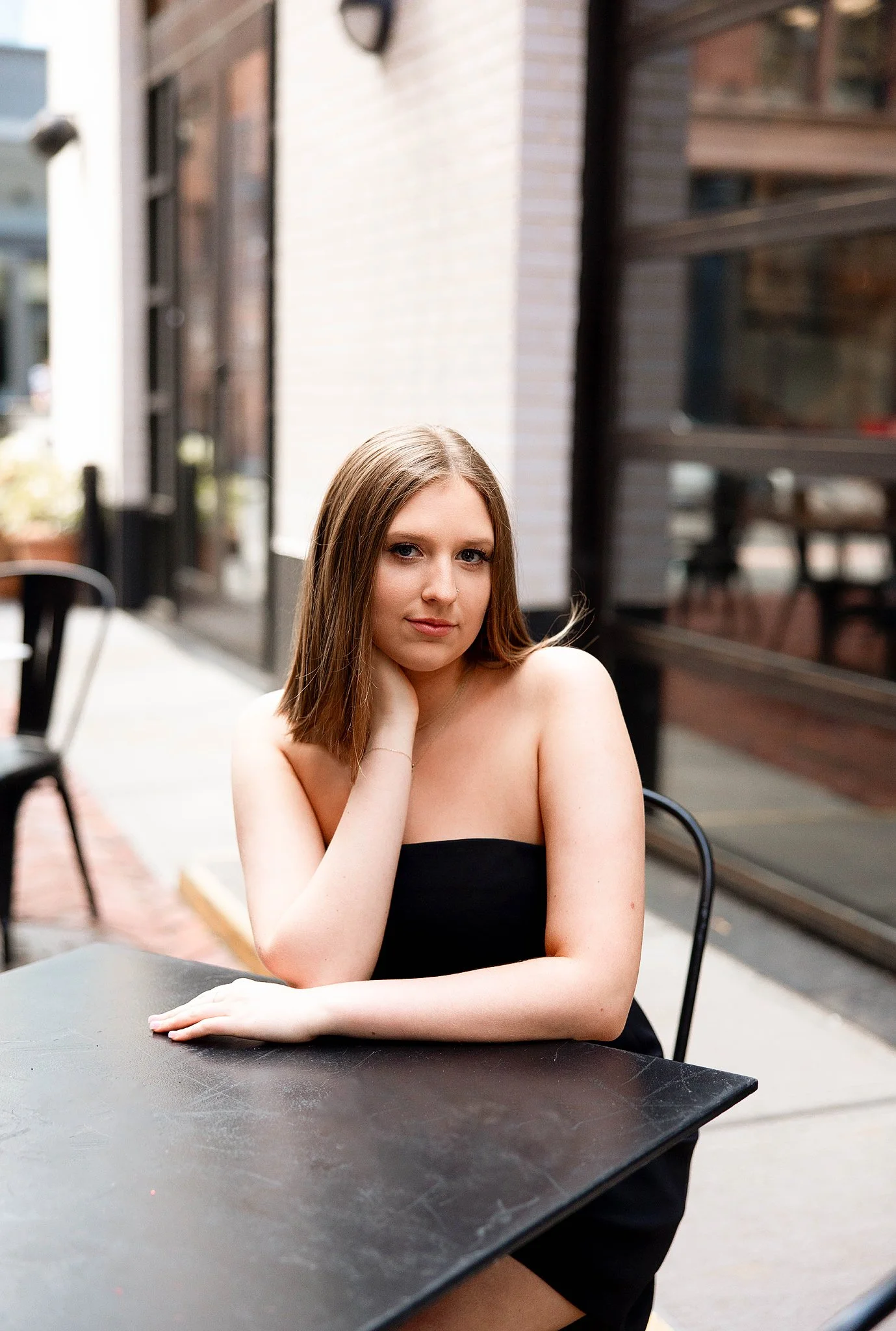 girls high school senior portrait taken in parker's alley of the senior sitting at a table nicely posed in a black dress