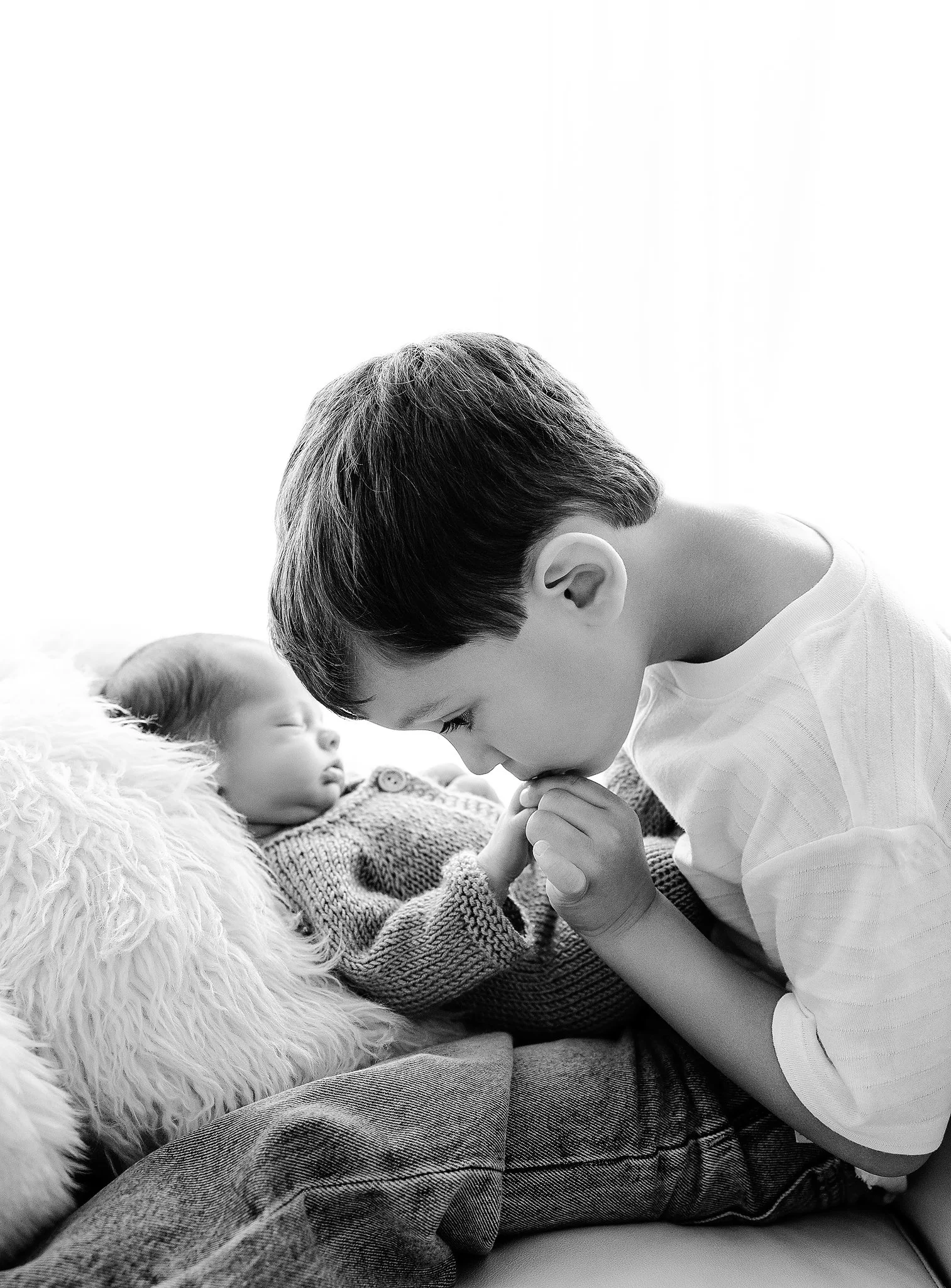 newborn baby cuddled with big brother during a studio photography session