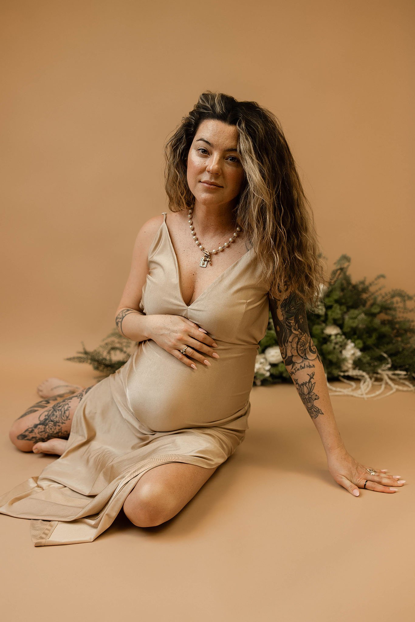 instudio maternity photoshoot of mother in  silky fitted dress to show off her belly bump