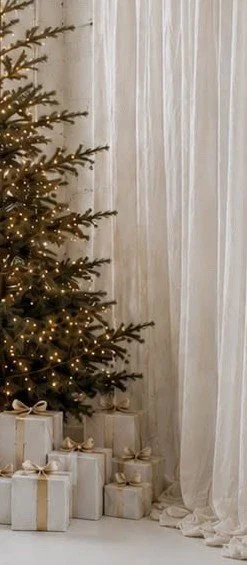 Photo studio for Family holiday mini sessions with a christmas tree, presents, twinkly lights and bright and airy vibes