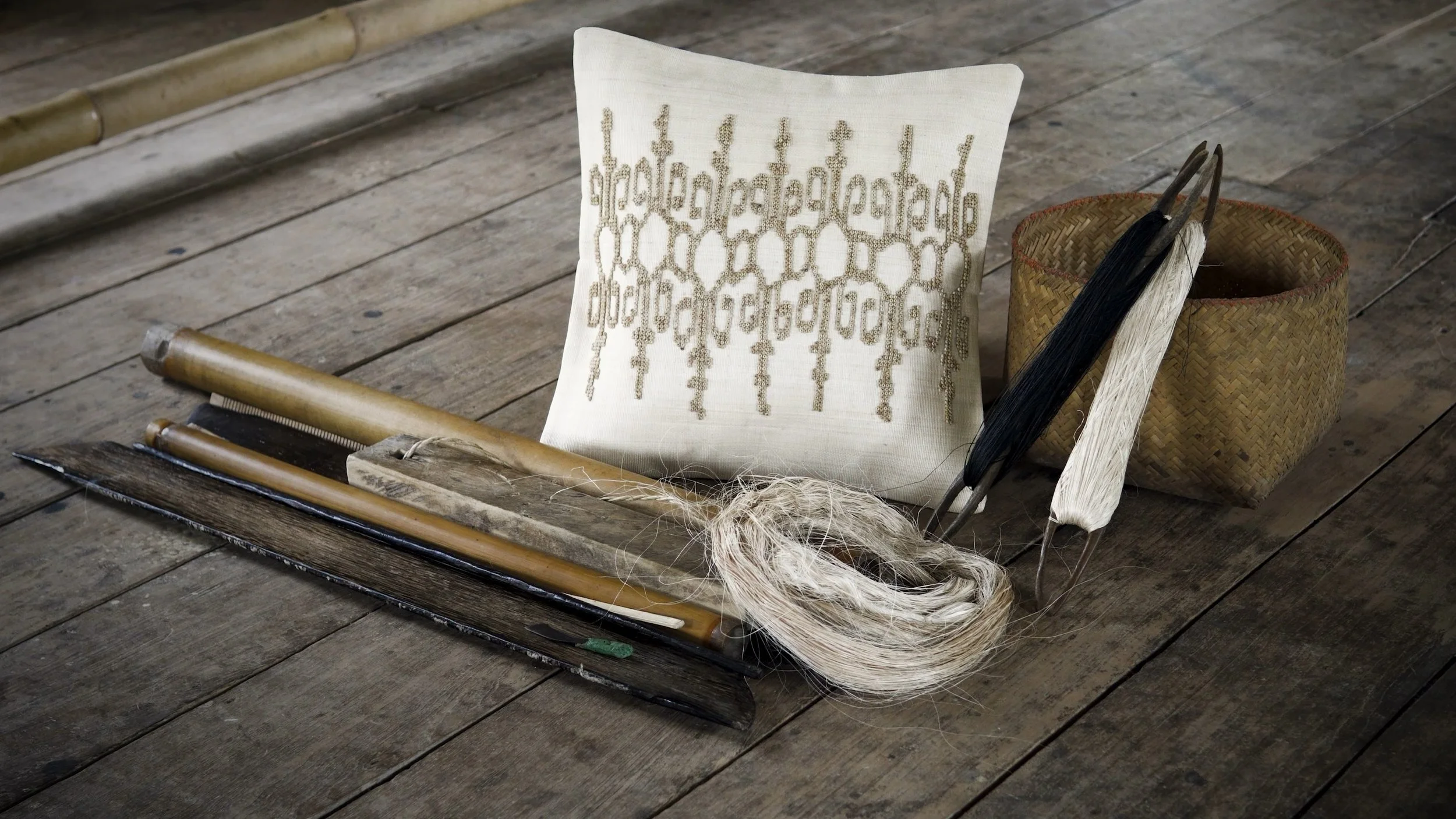 Handwoven Kubo cushion with natural fibers and traditional Filipino weaving tools.