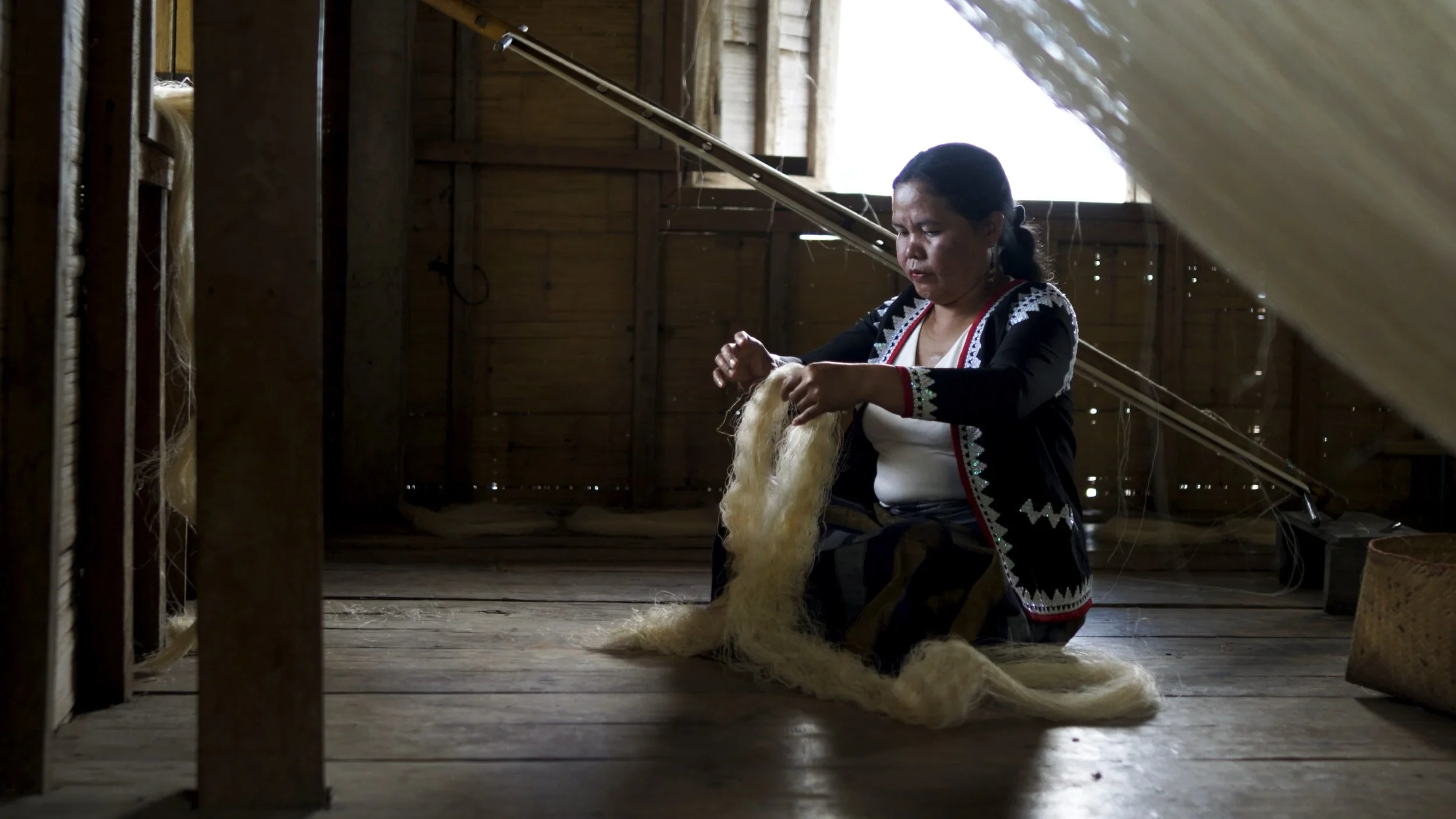 Artisan weaving natural fibers by hand using traditional techniques.