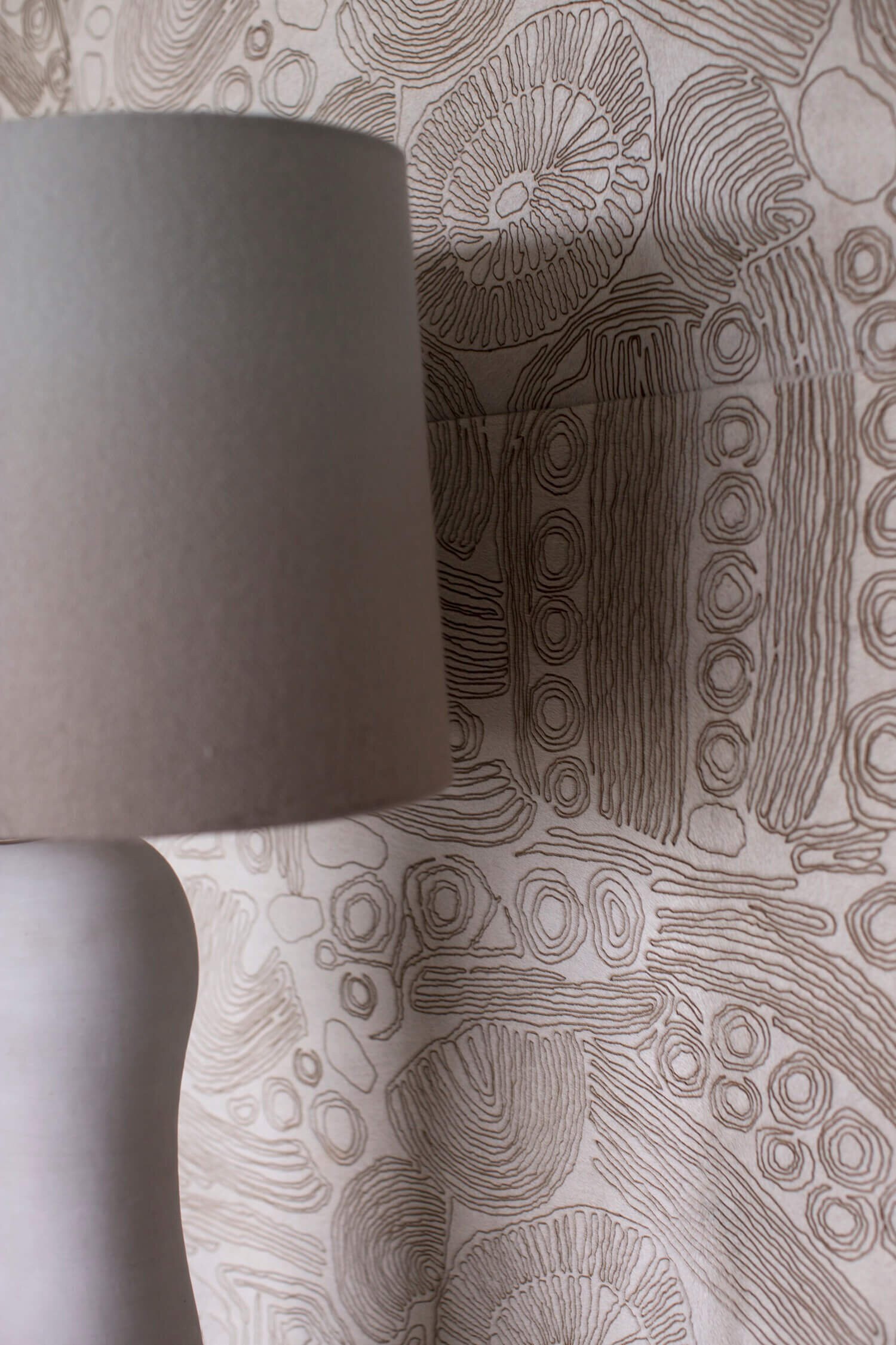 A Lamp with a ombre fabric shade in front of a upholstered wall made of Capricorn  ‘Jonathan’ Hide 